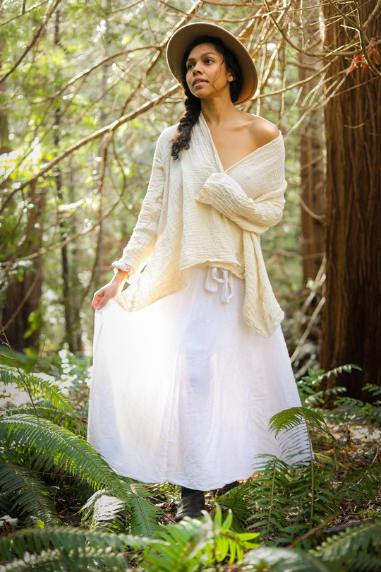 Female is clothed in natural white wrap on top with white, lightweight cotton skirt.