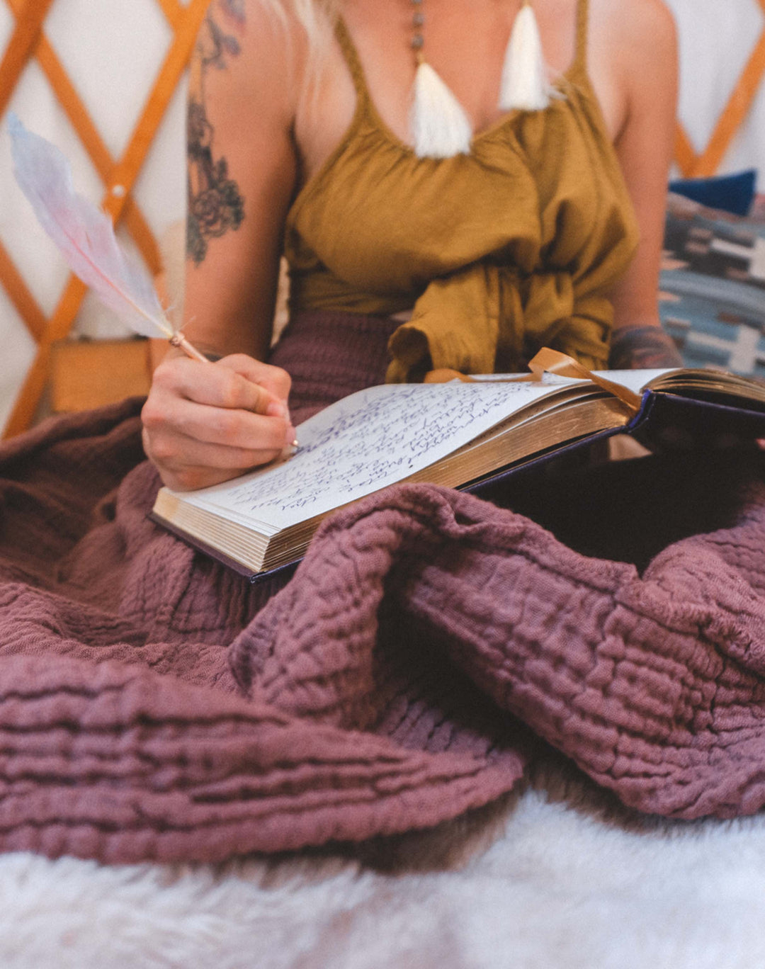 Model writes in book which is atop her purple crinkle skirt.