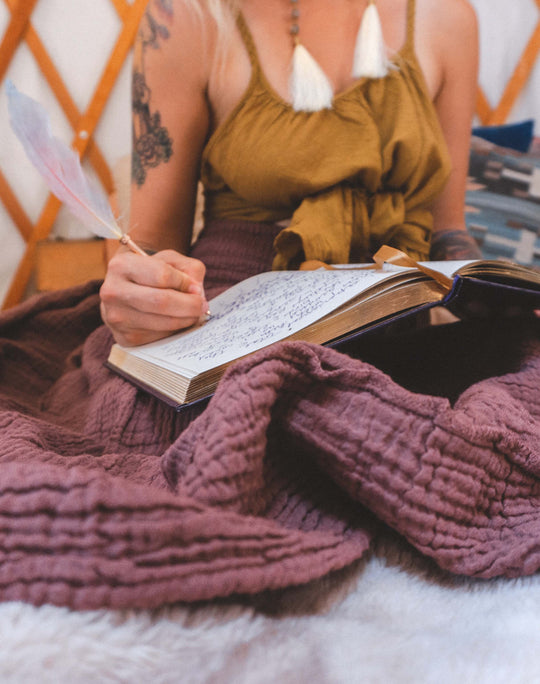 Model writes in book which is atop her purple crinkle skirt.